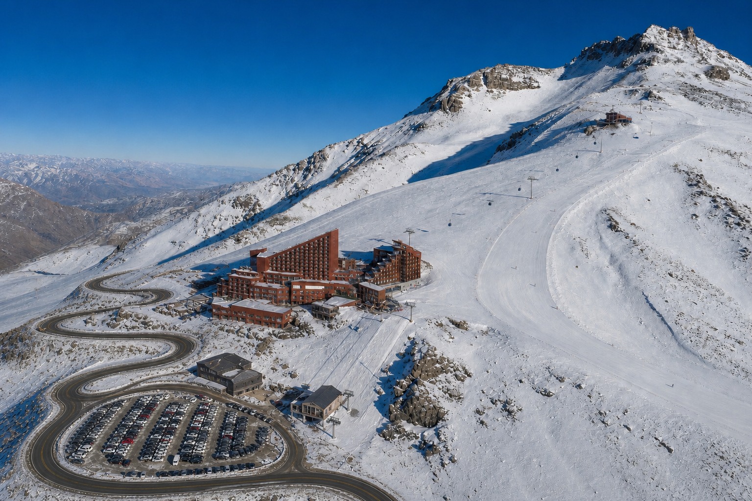 Foto aérea da encosta do Valle Nevado no inverno: a base do Valle Nevado a 3.000 metros, a gôndola vermelha subindo até o Bar Bajo Zero a 3.200 metros e a pista mais alta a 3.765 metros.